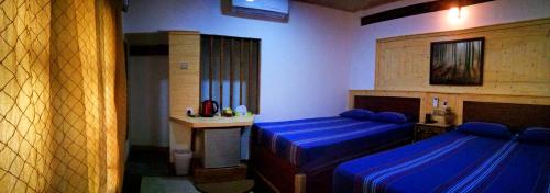 a room with two beds and a table in it at Green Cottage in Anuradhapura