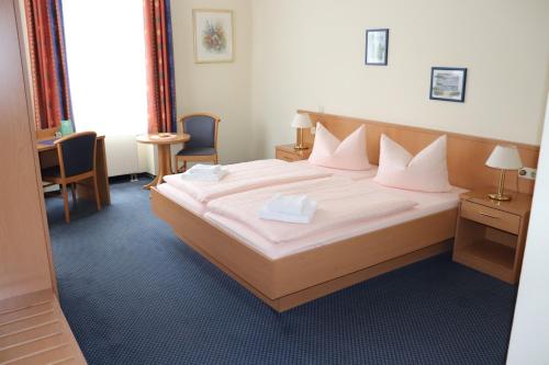 a bedroom with a large bed with white sheets and pillows at Hotel Saar in Kusel
