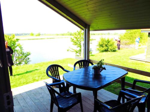 a table and chairs on a porch with a view of the water at Tangloppen Camping & Cottages in Ishøj