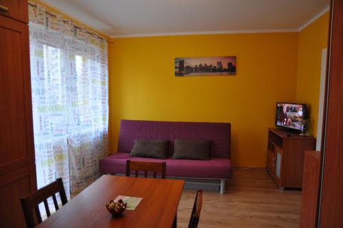 uma sala de estar com um sofá roxo e uma mesa em Apartament Big Boss em Świnoujście