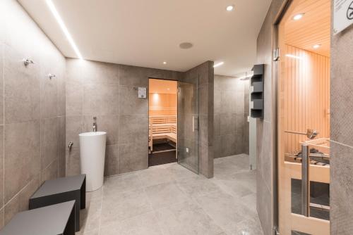 a bathroom with a walk in shower and a tub at Randolins Familienresort in St. Moritz