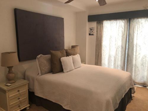 a bedroom with a white bed with a tv on the wall at Brownes Condominium 1 in Bridgetown
