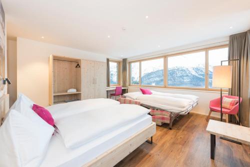 a bedroom with two beds and a table and chairs at Randolins Familienresort in St. Moritz