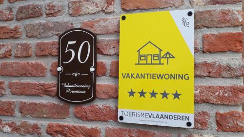 a sign attached to a brick wall with a house at Florentinus met hottub, afgesloten tuin en overdekt terras in Veurne