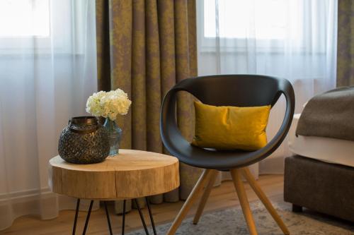 a black chair with a yellow pillow sitting on a table at Hotel Grüner Baum in Zell am See