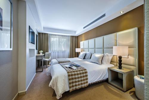 キンタ・ド・ラーゴにあるFour Seasons Country Clubの大きなベッドとデスクが備わるホテルルームです。