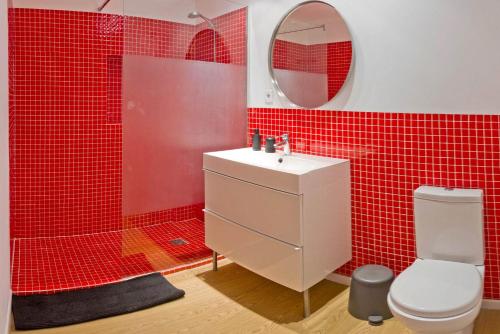 a red tiled bathroom with a sink and a toilet at ALCUDIA-VIDA SANA-PRIMERA LINEA DE MAR in Alcudia