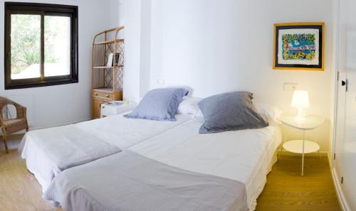 a bedroom with a large white bed with blue pillows at ALCUDIA-VIDA SANA-PRIMERA LINEA DE MAR in Alcudia