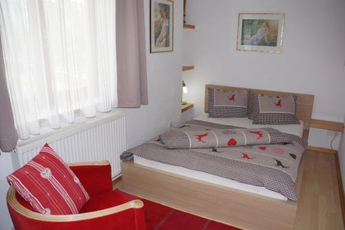 um quarto com uma cama e uma cadeira vermelha em Haus Juen em Tulfes