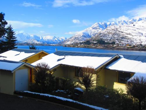 a row of houses with snow covered roofs and mountains at Villa Del Lago in Queenstown