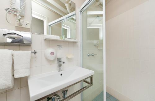 a white bathroom with a sink and a shower at Forrest Hotel & Apartments in Canberra