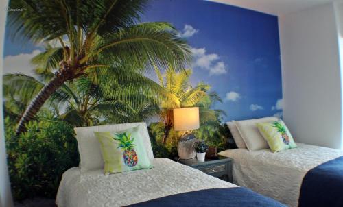 a bedroom with two beds and a palm tree mural at Departamento de lujo Antofagasta in Antofagasta