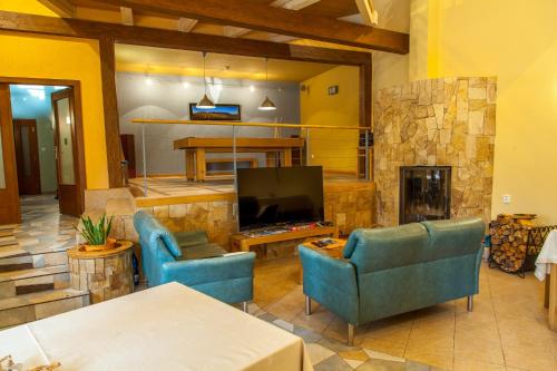 a living room with two blue chairs and a television at Penzion u Pejtrika in Mengusovce