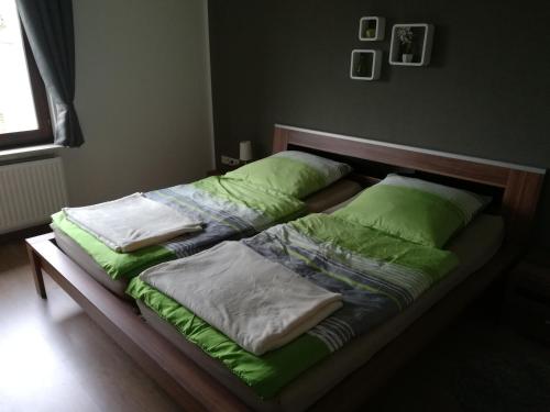 a bed with green sheets and pillows on it at Ferienwohnung Wichtelgarten in Kranenburg