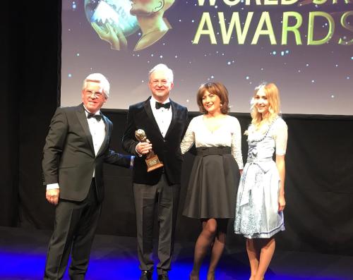 a group of three people holding an award on a stage at Hotel FIS Jasná in Demanovska Dolina