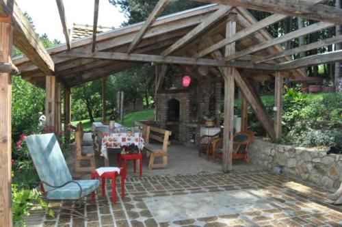 a pavilion with a table and chairs and a stone fireplace at Apartments Borove Noci in Vrdnik