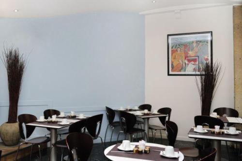 a dining room with tables and chairs and a painting at Hôtel Albe Saint Michel in Paris