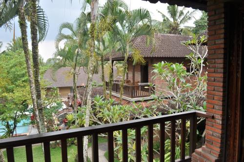 a house with a balcony and palm trees at Jati 3 Bungalows in Ubud