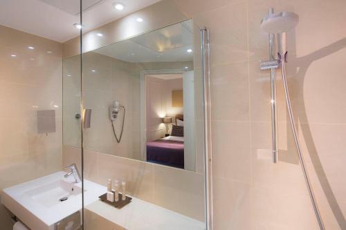 a bathroom with a shower and a sink and a mirror at Hôtel Galileo Champs Elysées in Paris