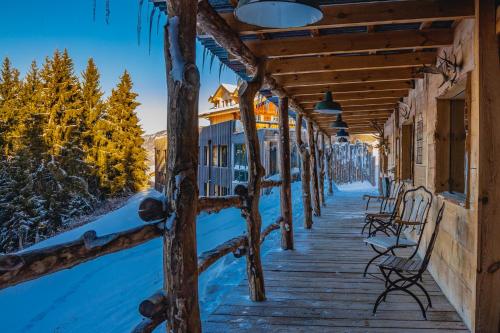 eine Holzterrasse mit Bänken und schneebedeckten Bäumen in der Unterkunft Rinderberg Swiss Alpine Lodge in Zweisimmen