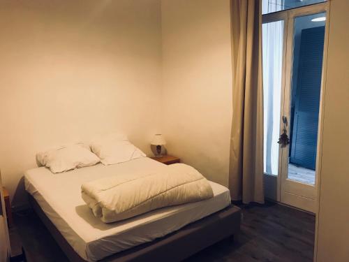 a bed with white sheets and a window in a room at Maison Banyuls in Banyuls-sur-Mer