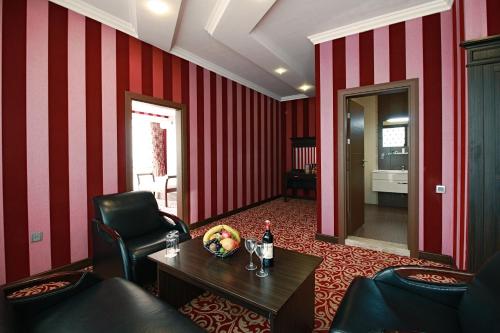 a room with red striped walls and a table with a bottle of wine at New Baku Hotel in Baku
