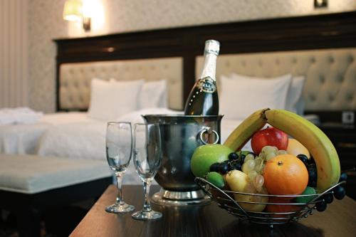 a bowl of fruit on a table with a bottle of champagne at New Baku Hotel in Baku