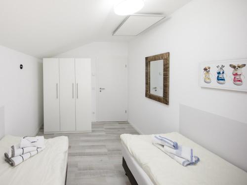 een witte kamer met 2 bedden en een spiegel bij Haus Emil in Cuxhaven