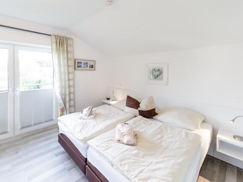 a white bedroom with two beds and a window at Haus Emil in Cuxhaven