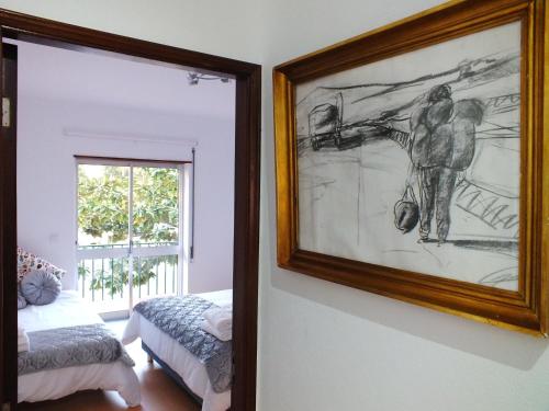 a painting hanging on a wall next to a bedroom at Clarinha House in Fátima