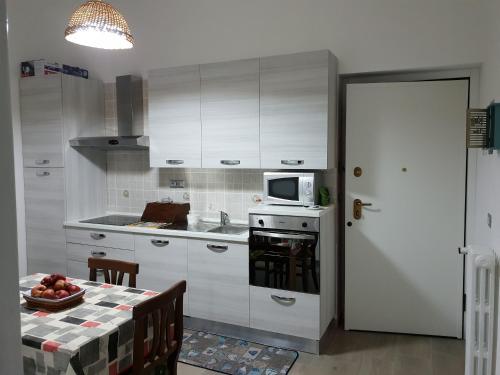 eine Küche mit weißen Schränken, einem Tisch und einer Mikrowelle in der Unterkunft APPARTAMENTI DEI MILLE in Novi Ligure