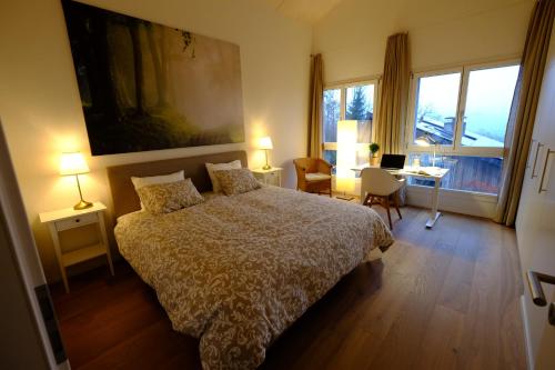 a bedroom with a bed and a desk and windows at Great View in Kehrsatz