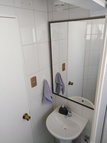 a white bathroom with a sink and a mirror at Hostal Boutique F in El Quisco