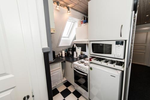 a kitchen with white appliances and a checkered floor at Toftegården Guesthouse - Rooms in Skagen