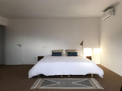 a white bedroom with a white bed with blue pillows at ZN Lodge in Vidago