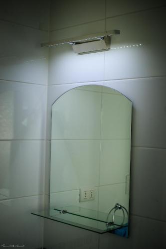 a mirror on a wall with a glass shelf at Marina Pichilemu in Pichilemu