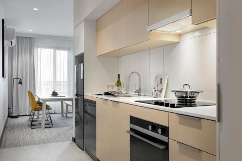a kitchen with white cabinets and a table in a room at Quest Notting Hill in Clayton North