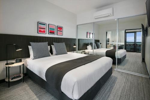 um quarto de hotel com duas camas e uma varanda em Quest Notting Hill em Clayton North