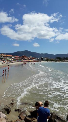 a group of people on a beach with the ocean at Pousada Mar Verde in Florianópolis