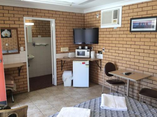 a kitchen with a refrigerator and a tv on a brick wall at cross roads motel in Cobar