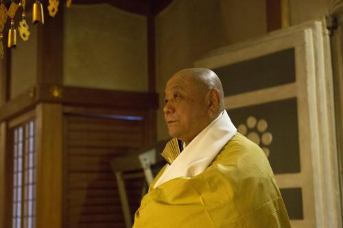 an older man in a yellow jacket standing in a room at 高野山 宿坊 総持院 -Koyasan Shukubo Sojiin- in Koyasan