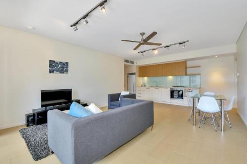 a living room with a gray couch and a kitchen at Darwin Waterfront Short Stay Apartments in Darwin