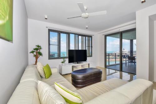 a living room with a white couch and a flat screen tv at Darwin Waterfront Short Stay Apartments in Darwin
