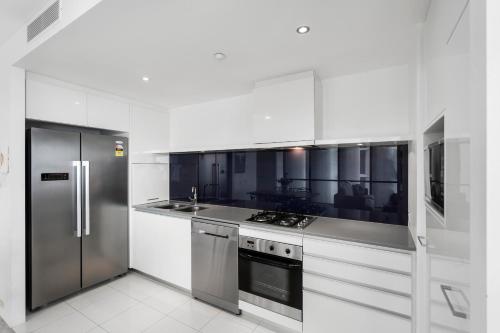 a white kitchen with a refrigerator and a stove at Circle on Cavill - Gclr in Gold Coast