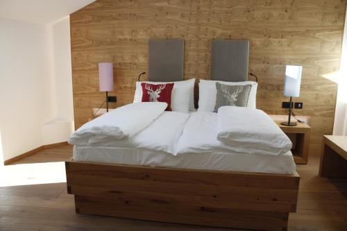 a bedroom with a large bed with white sheets and pillows at Gasthof Zum Hirschen Margreid in Magrè allʼ Adige