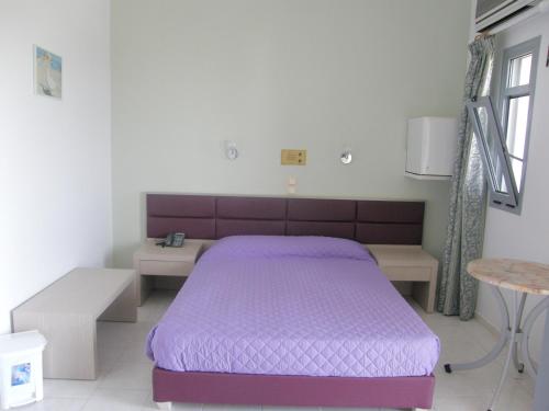 a bedroom with a purple bed and a table at Megim Hotel in Palaiochóra