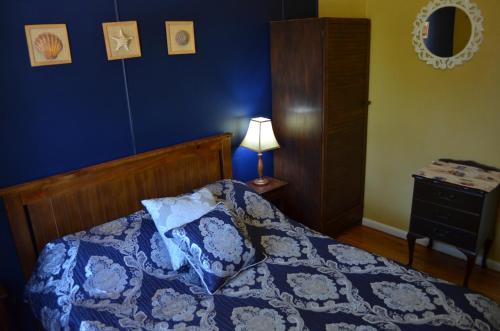 a blue bedroom with a bed and a lamp at Casa Husky in Huskisson