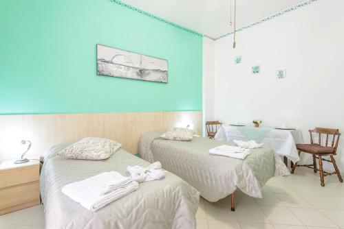リド・ディ・オスティアにあるB&B Soggiorno Di Ostiaのベッド2台、テーブル、椅子が備わる客室です。