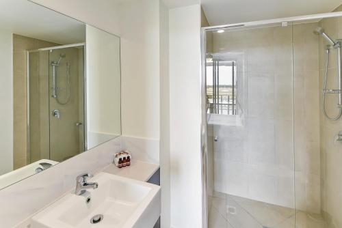 a white bath tub sitting next to a white sink at Direct Hotels - North Shore Kawana in Kawana Waters