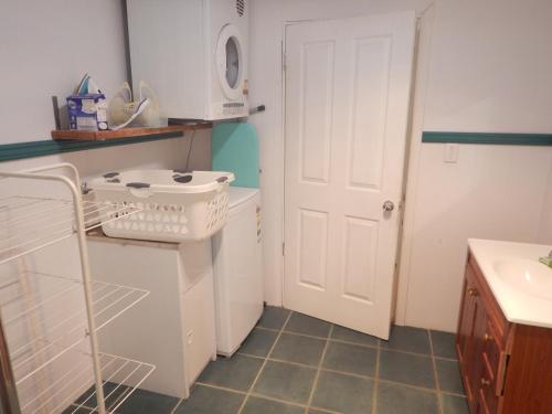 a kitchen with white cabinets and a white door at Pine Cottage in Brisbane